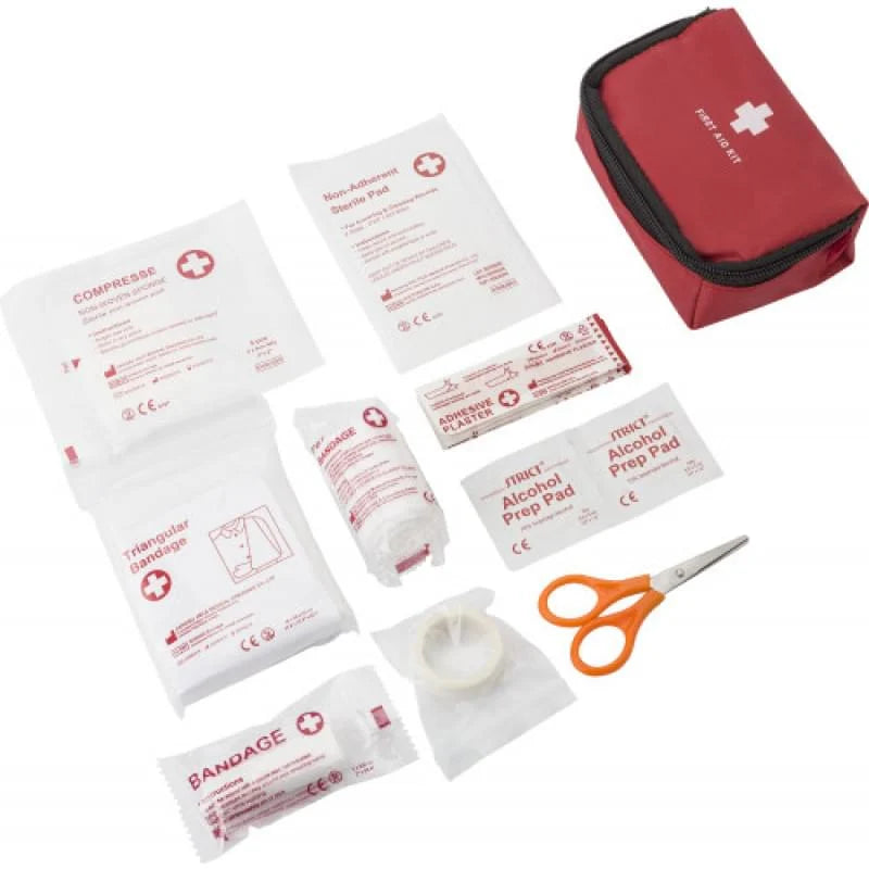 Compacte EHBO-set met pleisters, verband en schaar op witte achtergrond.